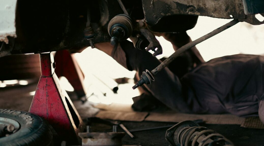 Monteur werkt onder een opgekrikte auto