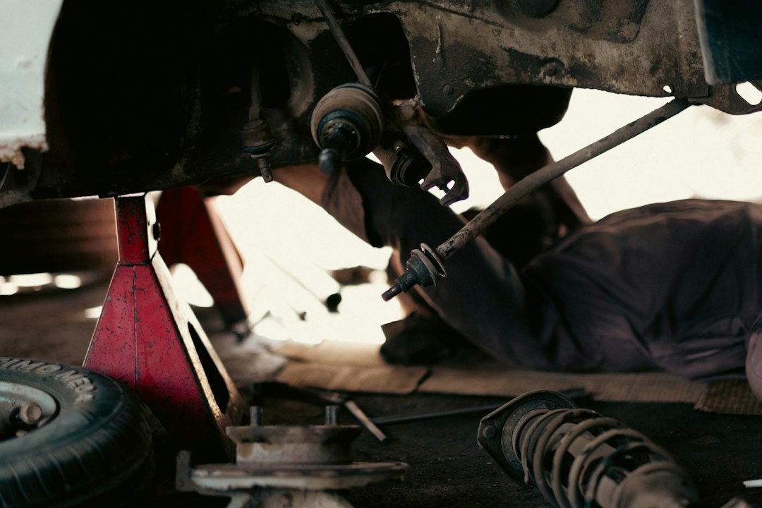 Monteur werkt onder een opgekrikte auto