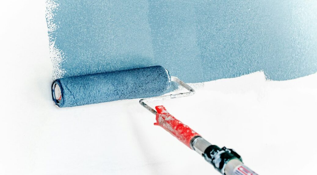 Een verfroller brengt blauwe verf aan op een witte wand