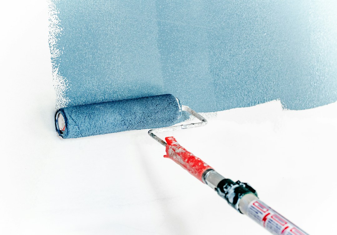 Een verfroller brengt blauwe verf aan op een witte wand